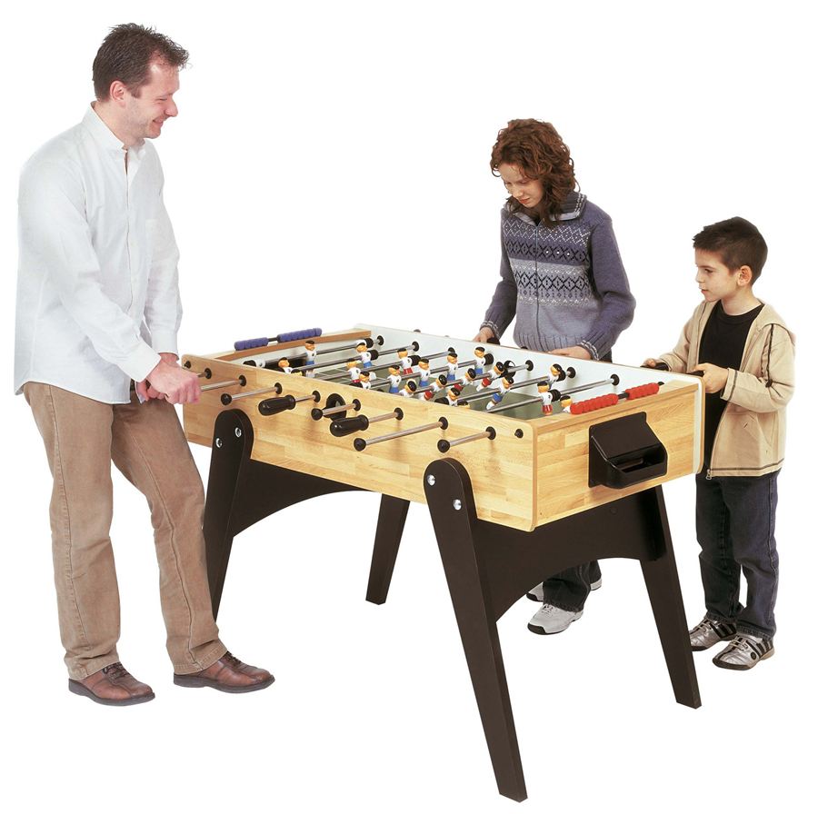 Drei Personen spielen gemeinsam an einem Tischkicker, während sie sich auf das Spiel konzentrieren.