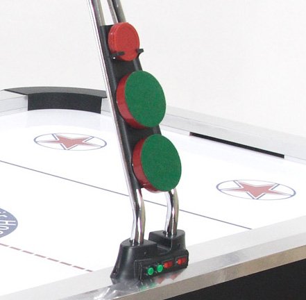Airhockey-Tisch mit roten und grünen Pucks, die an einer Halterung aufbewahrt werden, auf einer Spielfläche mit markierten Kreisen.