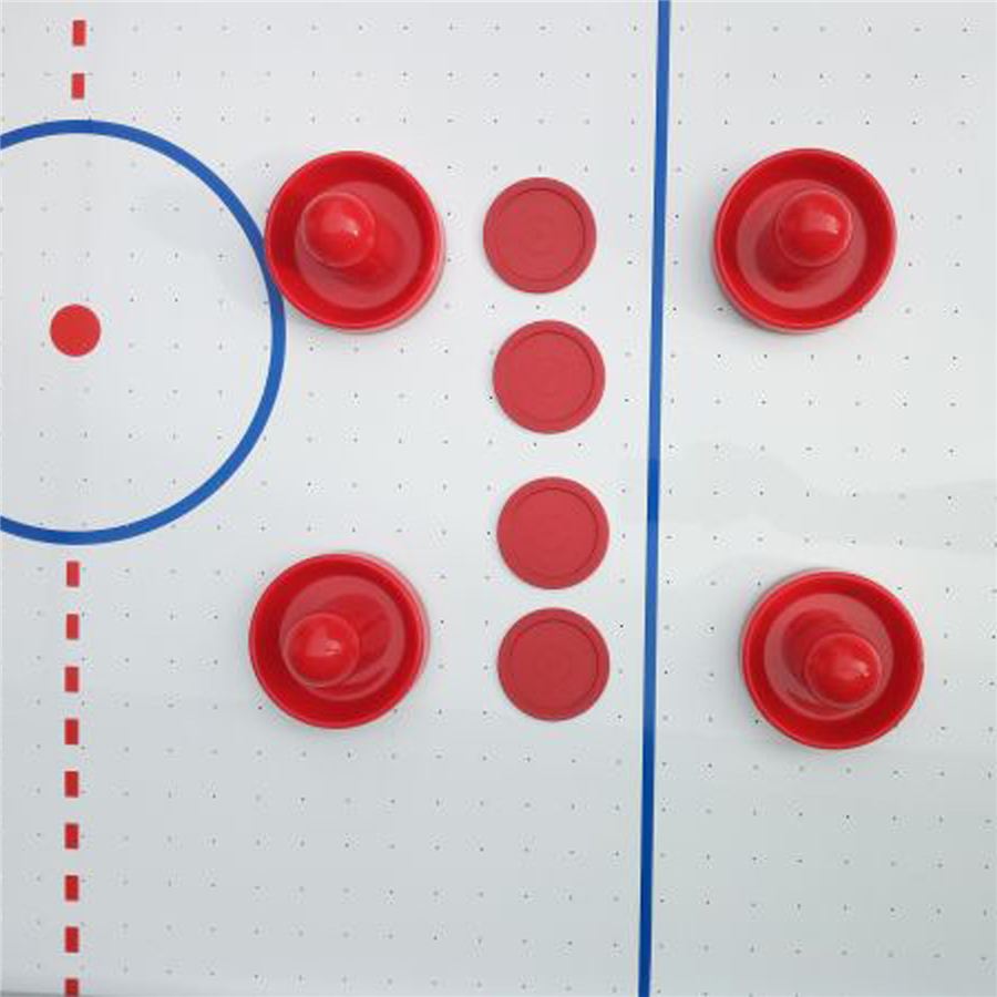 Vier rote Airhockey-Schläger und vier rote Pucks liegen auf einem weißen Airhockey-Tisch mit blauen und roten Spielfeldlinien.