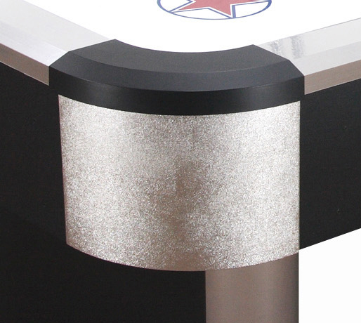 Ecke eines Airhockey-Tisches mit silbernem und schwarzem Design, zeigt eine glänzende Oberfläche und einen Teil des Spielfelds mit Sternmotiv.