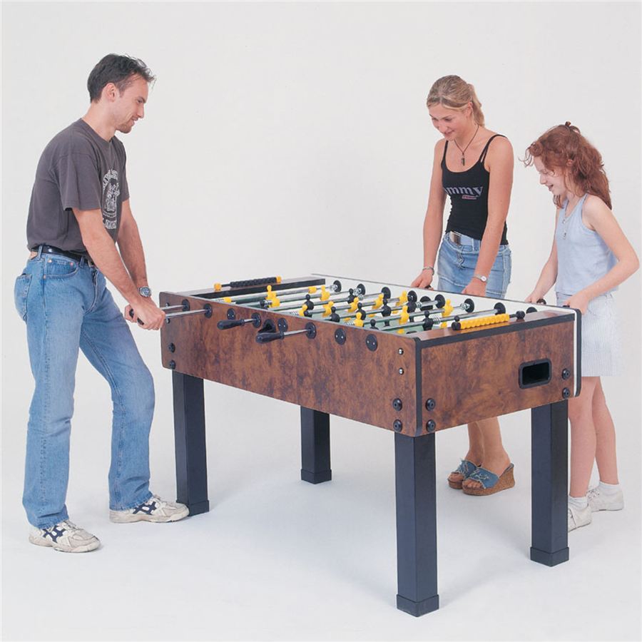 Drei Personen spielen gemeinsam an einem Tischkicker, lachen und konzentrieren sich auf das Spiel.